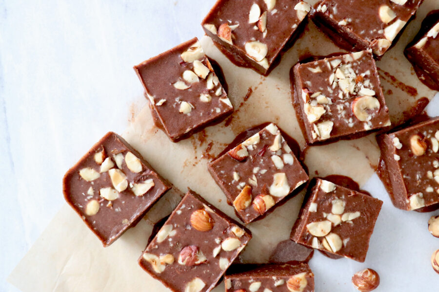 Chocolate hazelnut freezer fudge cut into squares and topped with hazelnuts.