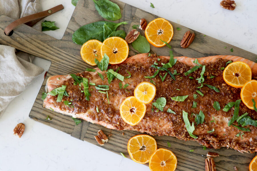 Pecan crusted salmon on grey wooden slab with orange slices.